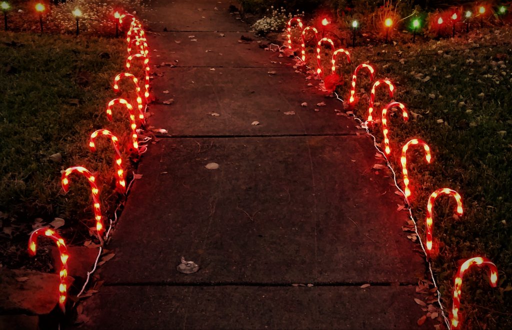 Rows of Glowing Candy Canes along a Walkway - Night